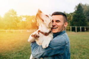 happy man smiling hugging hugging dog close 